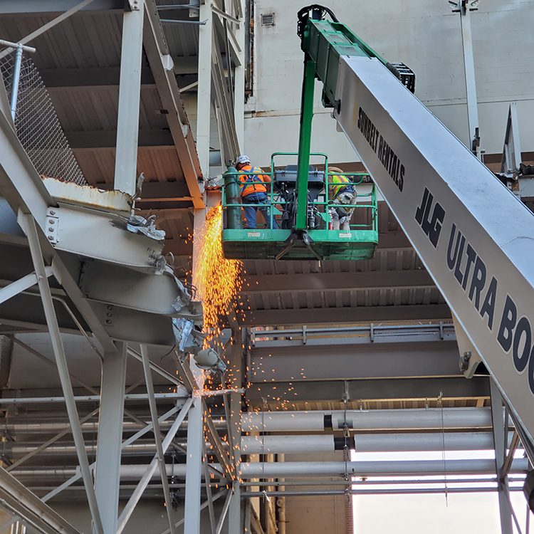 Worker in boom lift cutting steel for stadium demolition