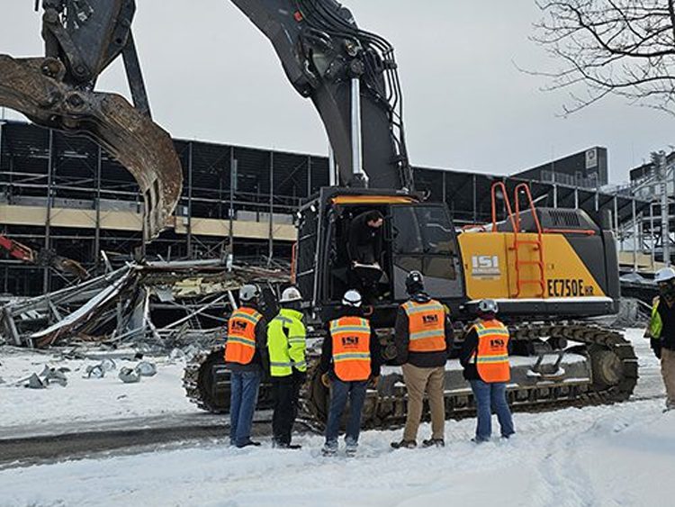 Crews standing in front of equipment during stadium demolition at Penn State