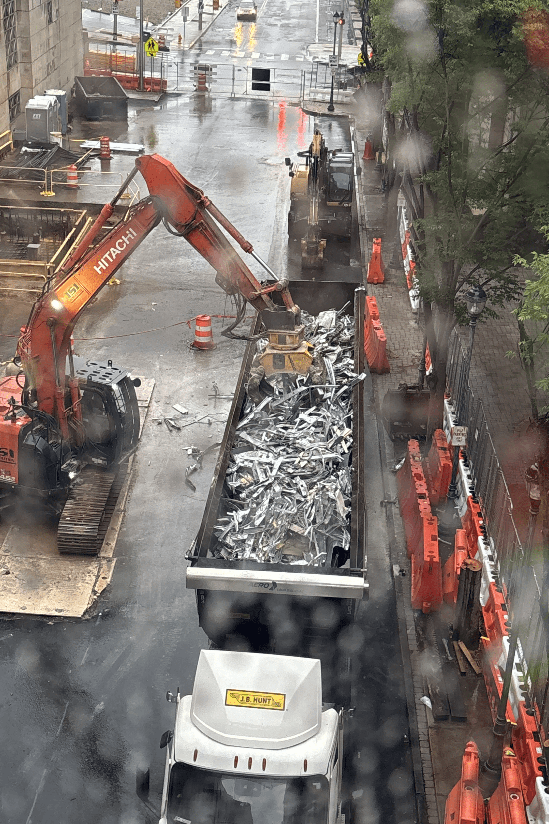 Staging area with an excavator loading debris into a dumpster