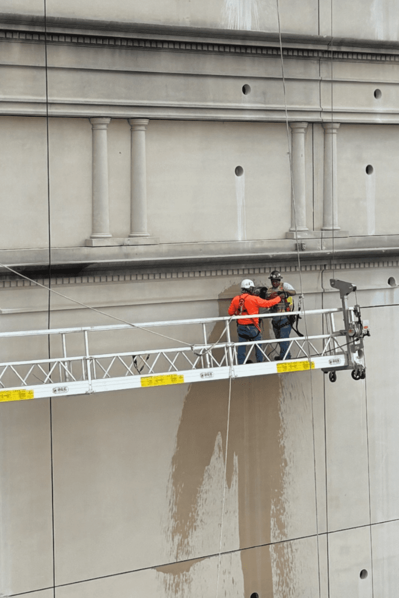 Construction crews on scaffolding using a core drill during demolition