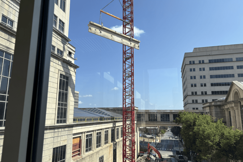 Large cement pieces being removed by crane from a 10-story office building during structural demolition