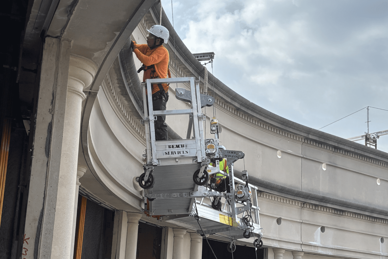 Crews on a lift drilling holes to facilitate the removal of cement panels during demolition. 