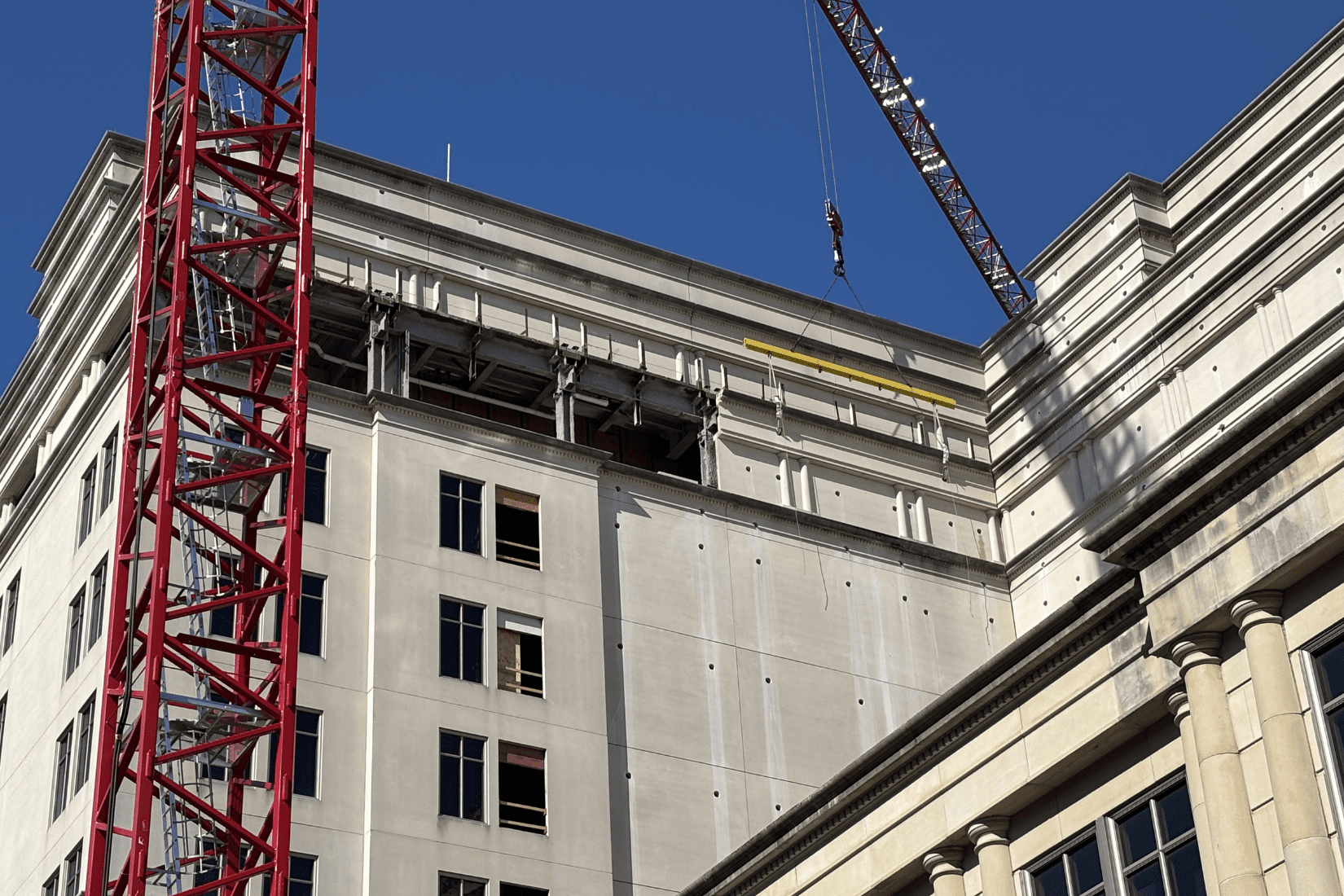 Crews work with a crane  to remove concrete panels from 10-story office building during structural demolition