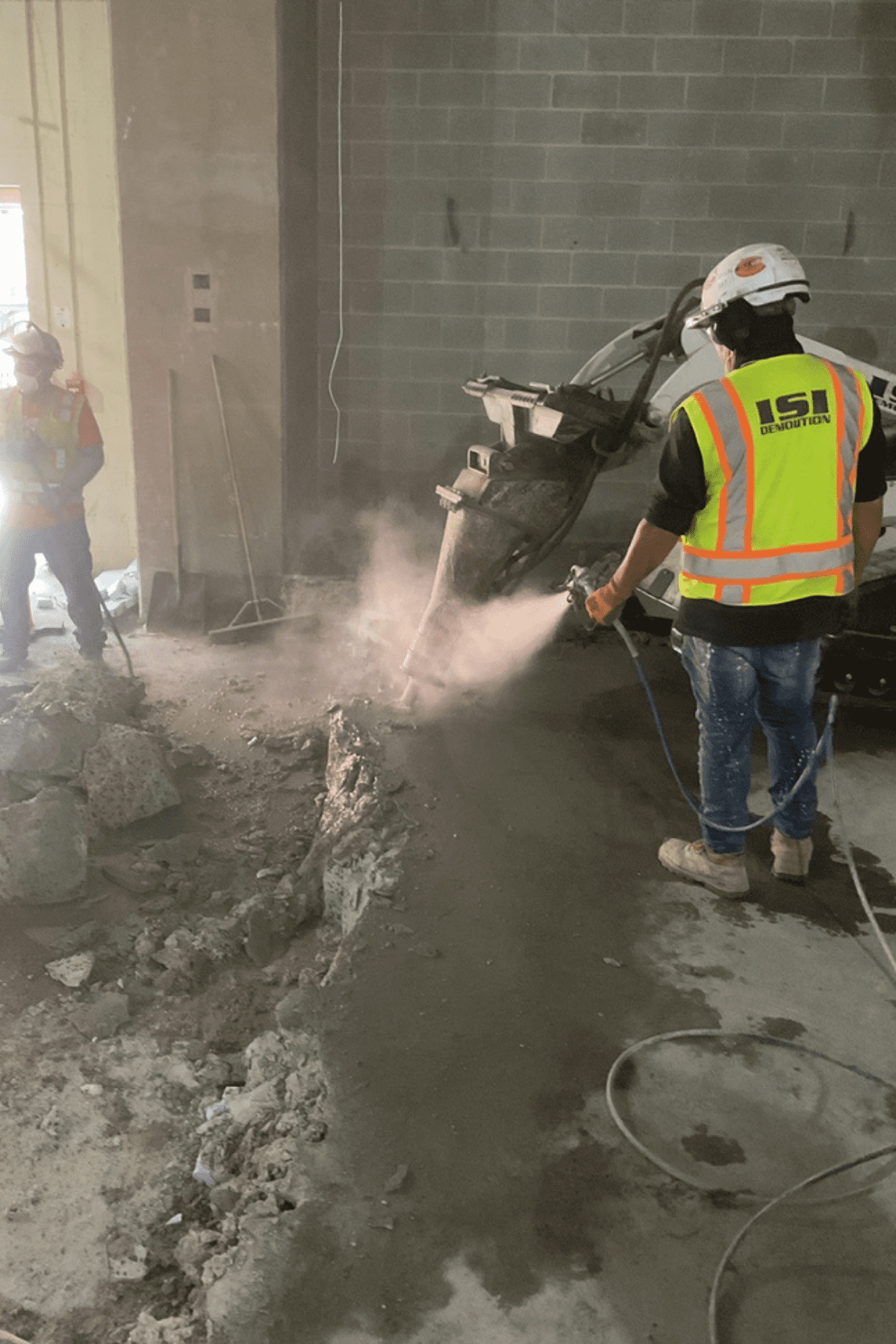 Crews using dust mitigation techniques around robotic demolition equipment