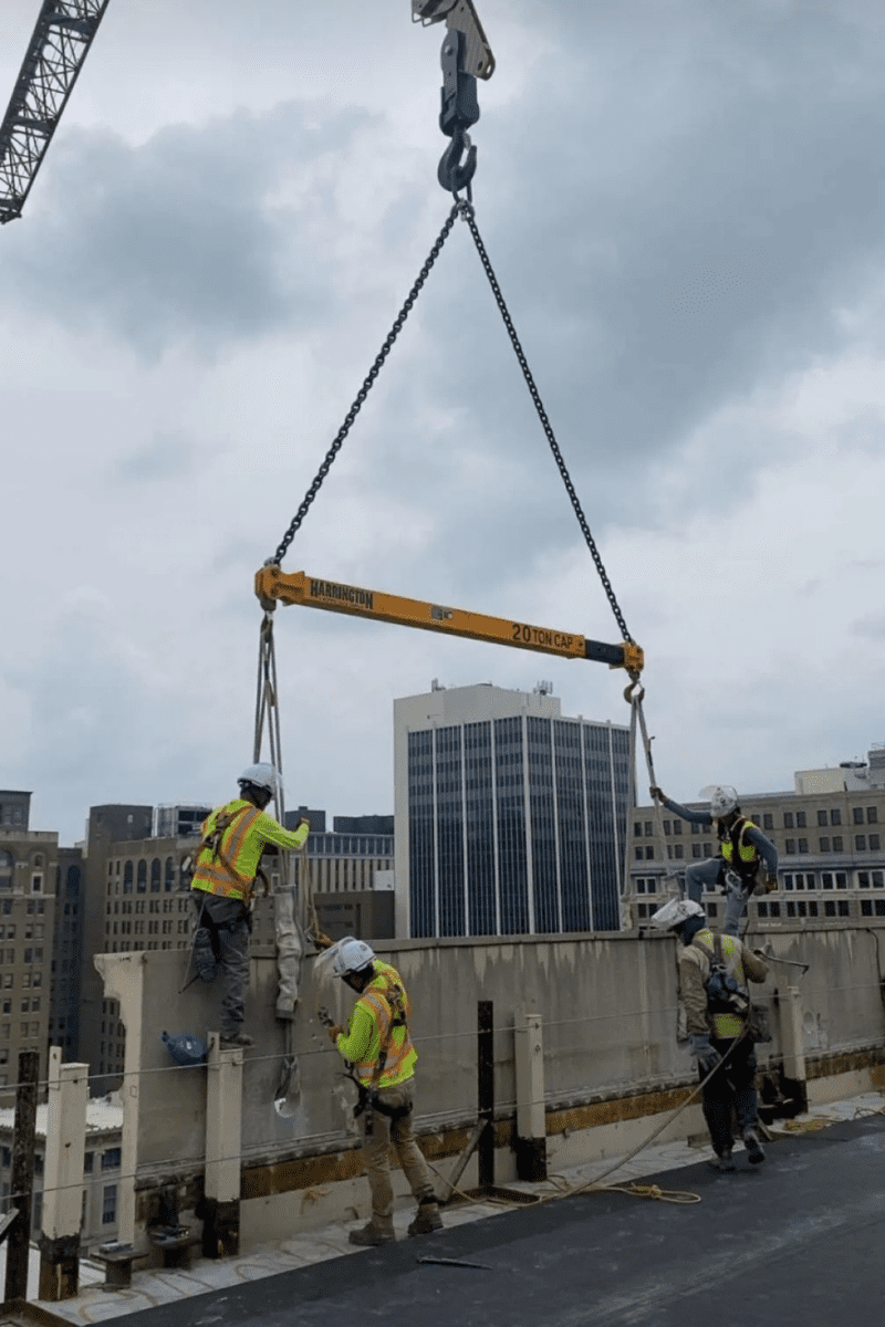 Crews attaching cement panels to a crane during structural demolition