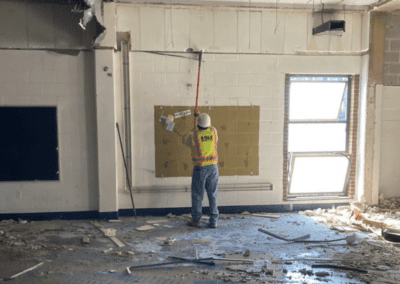 Demolition worker removing material from the wall inside a school