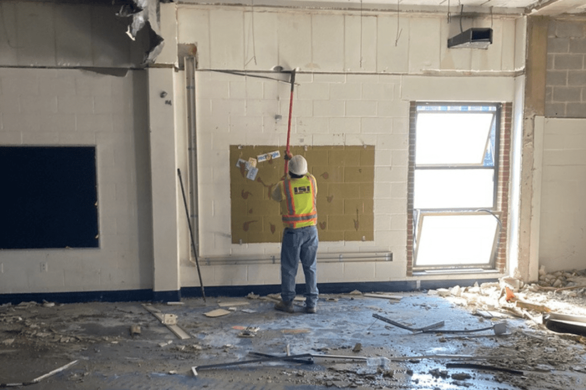 Demolition worker removing material from the wall inside a school