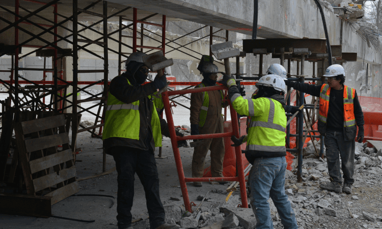 crews installing scaffolding to secure the construction site