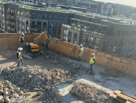 Robotic demolition on a rooftop with crews nearby